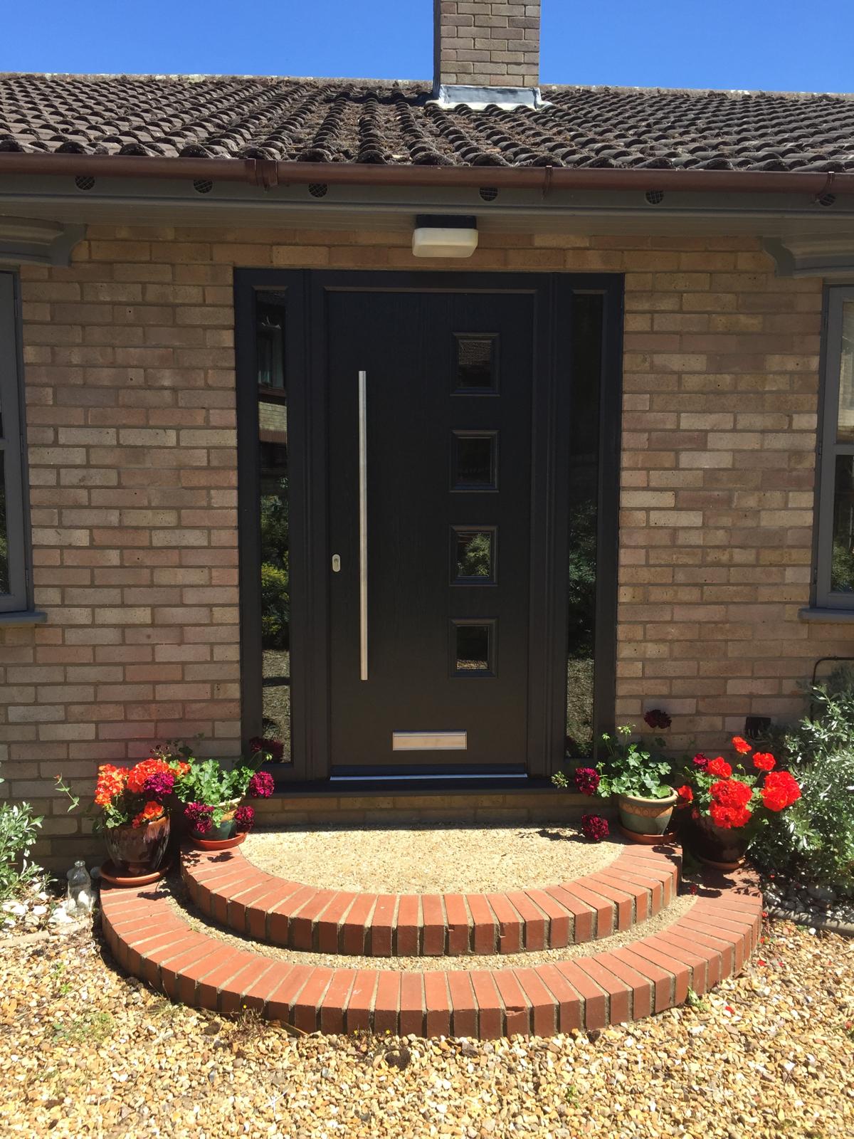 Black front door with glazed side panels and curved brick steps fitted near Cambridge