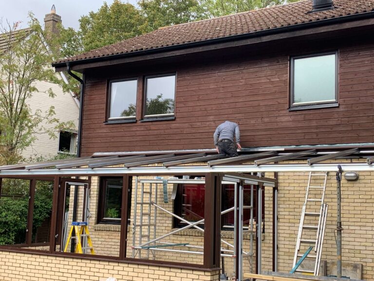 Conservatory roof being replaced on a brick and timber-clad house