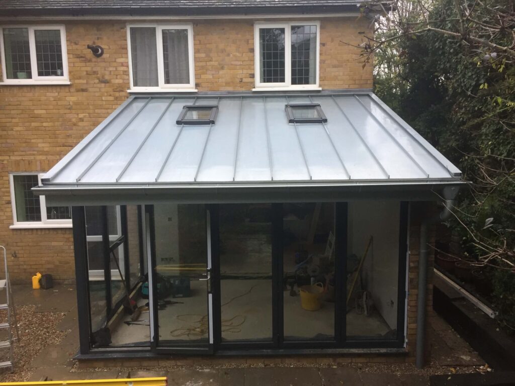Extension with a standing-seam metal roof, rooflights and bi-fold doors