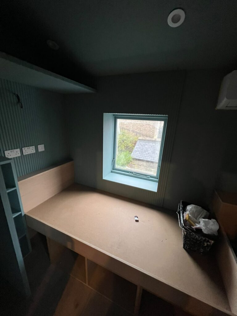 Built-in desk under a window in a study with reeded panelling