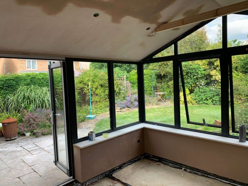 Conservatory interior with dark-framed glazing before finishing