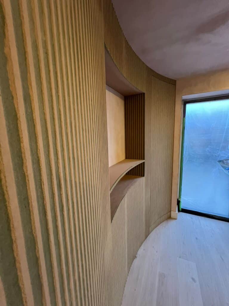 Curved niche with shelves set into a fluted wall beside a garden door