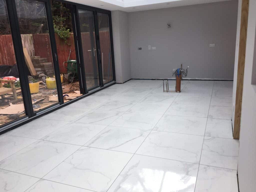 New extension with large white floor tiles and bi-fold doors