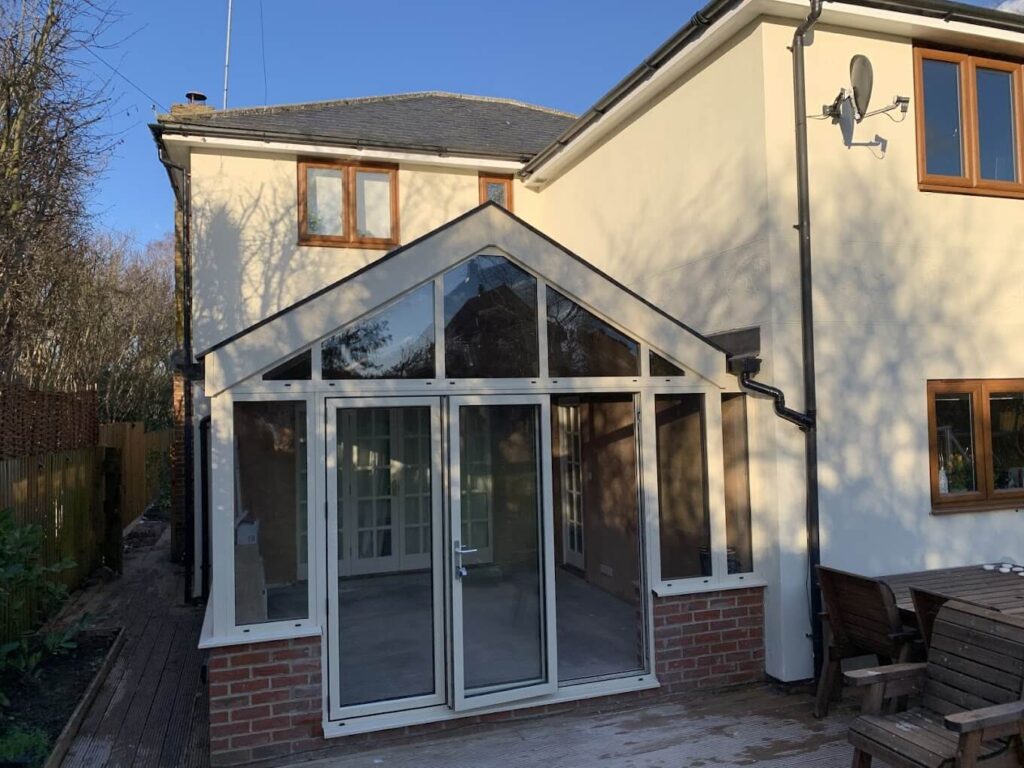 Gable-fronted conservatory with French doors on a rendered house