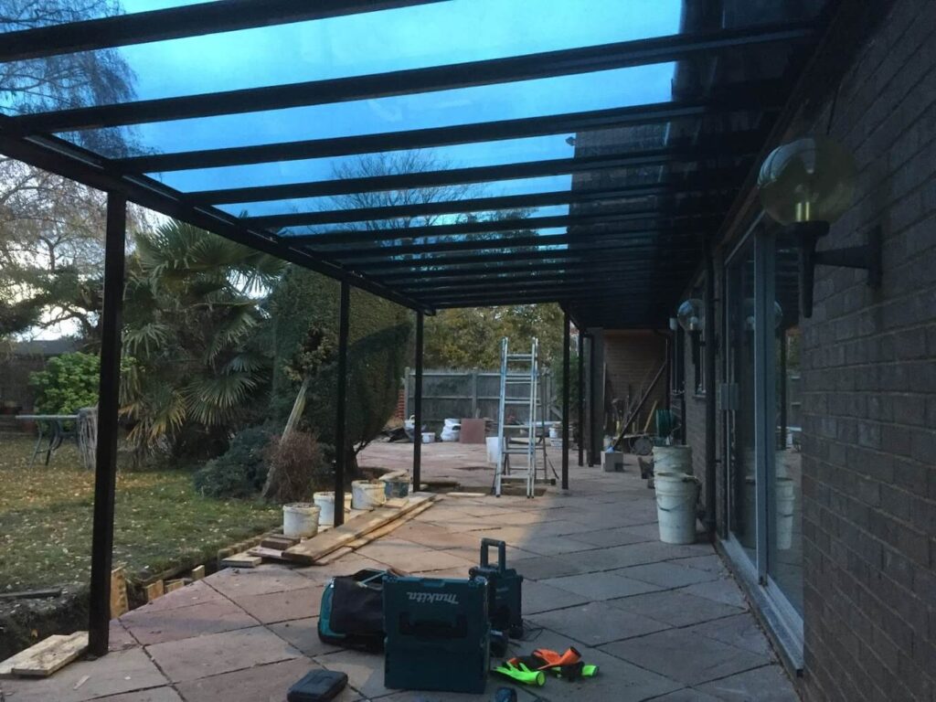 Glass-roofed veranda being installed along the back of a house
