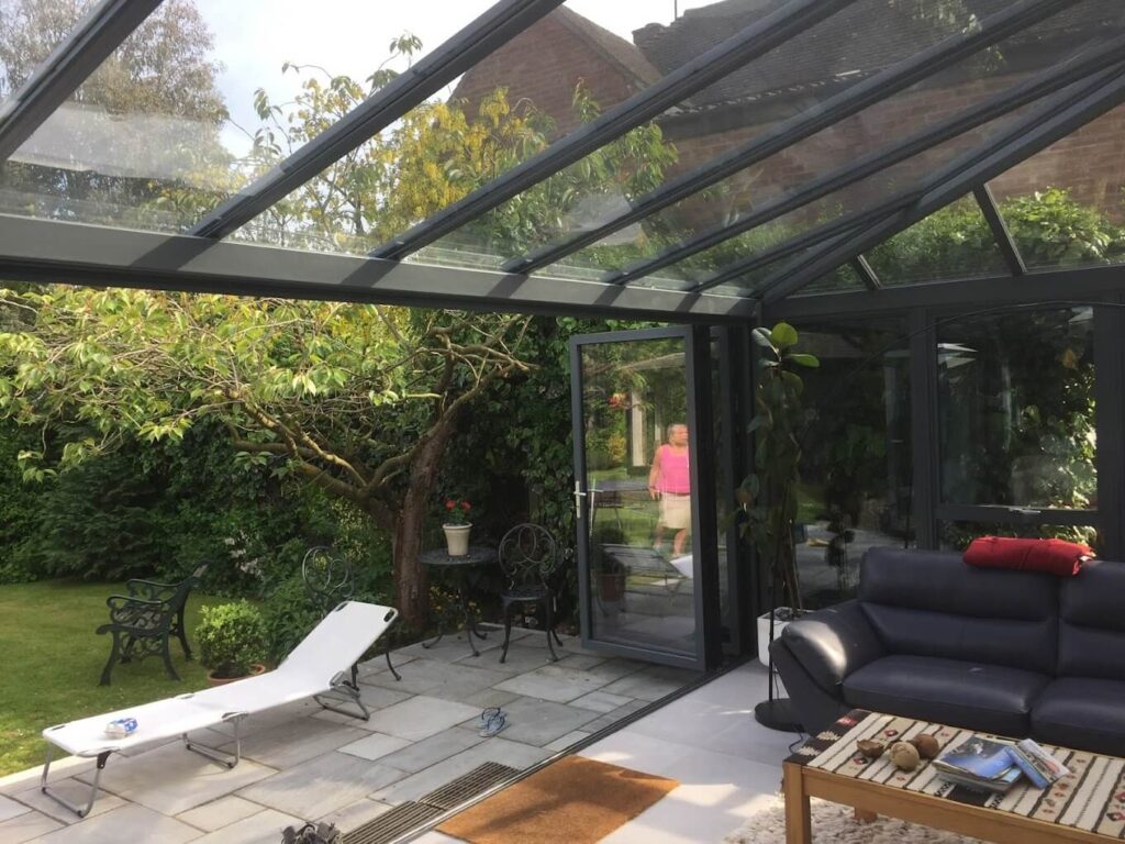 Glass-roofed veranda over a patio with garden furniture