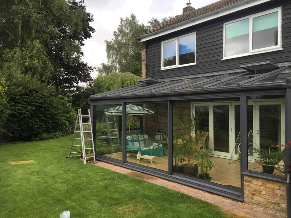 Conservatory with grey frames and a solid roof on a clad family home
