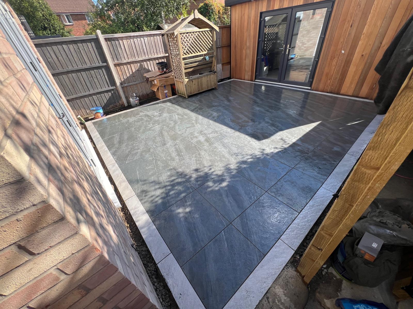 Completed grey porcelain patio beside a timber-clad garden studio