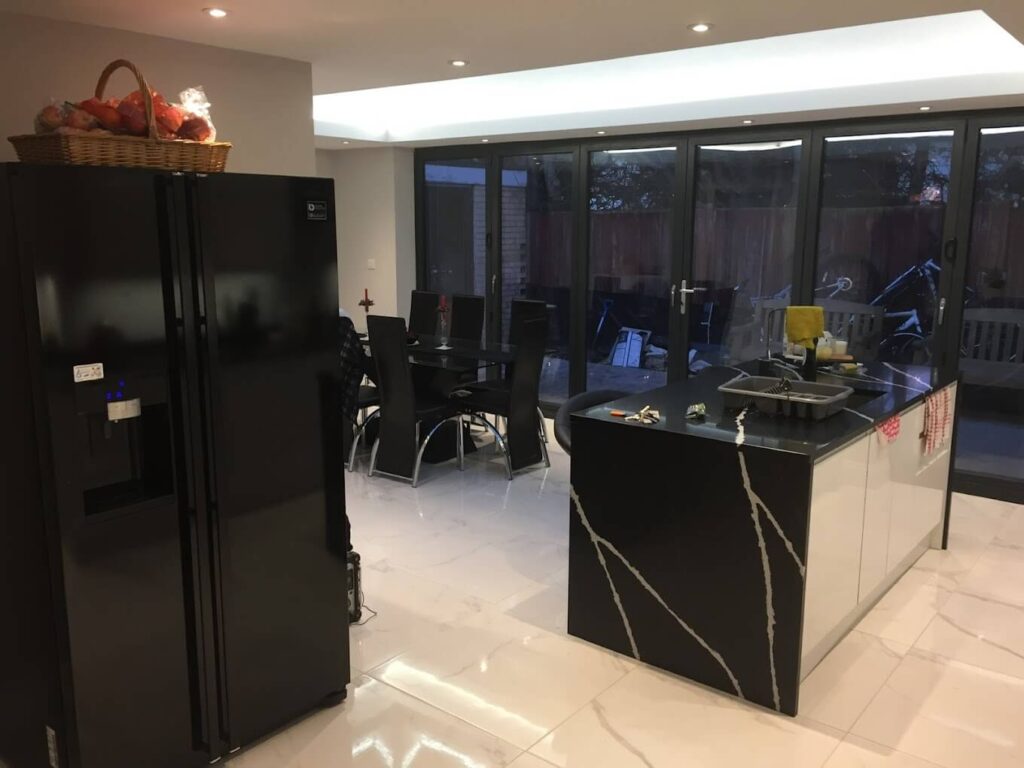 Kitchen with a dark island and marble-effect worktop in an open-plan extension