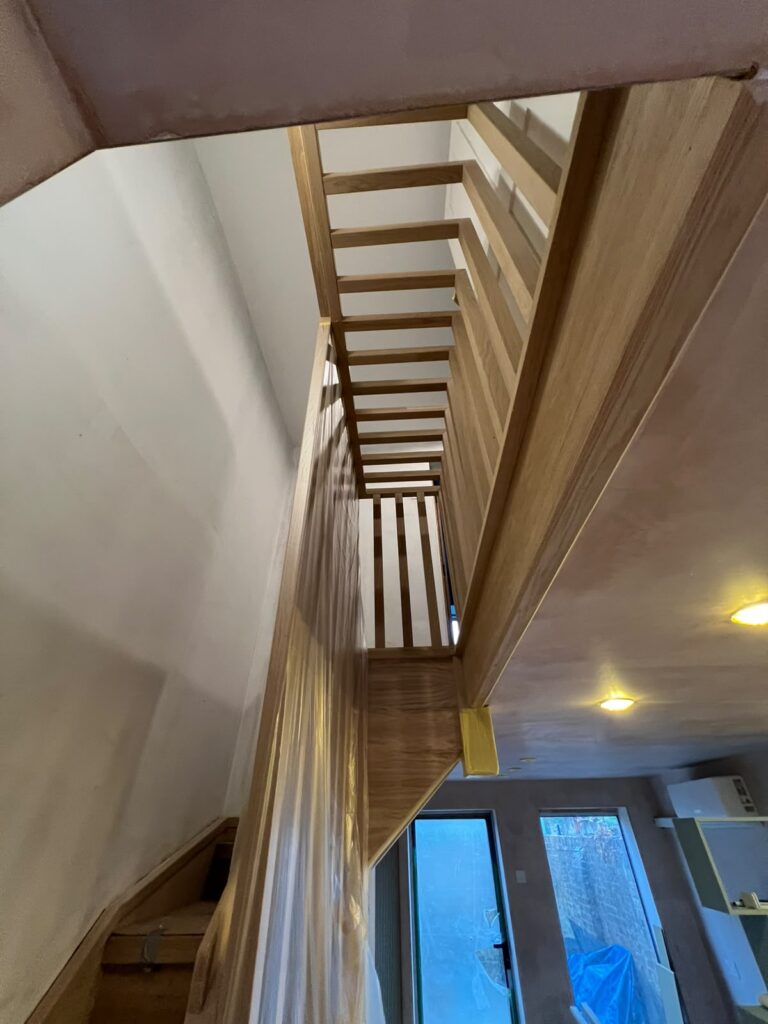 Looking up an oak staircase with slatted oak screen